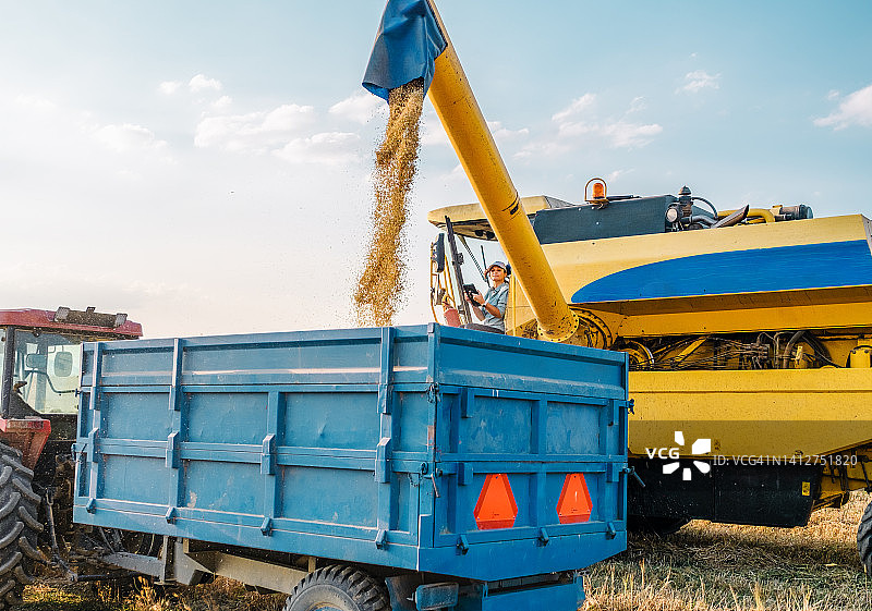 坐在联合收割机上使用平板电脑的女农图片素材