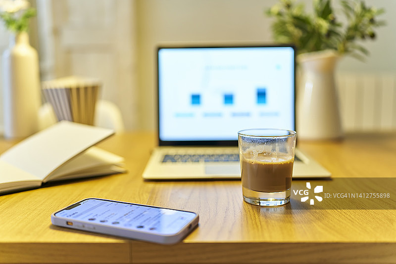 工作区牛奶咖啡杯特写，旁有笔记本电脑和智能手机图片素材