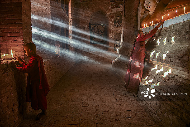 在缅甸蒲甘寺庙内祈祷的两位年轻佛教僧侣图片素材