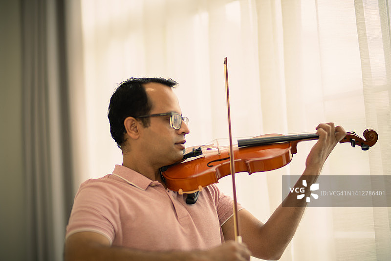 男人在家练习小提琴图片素材