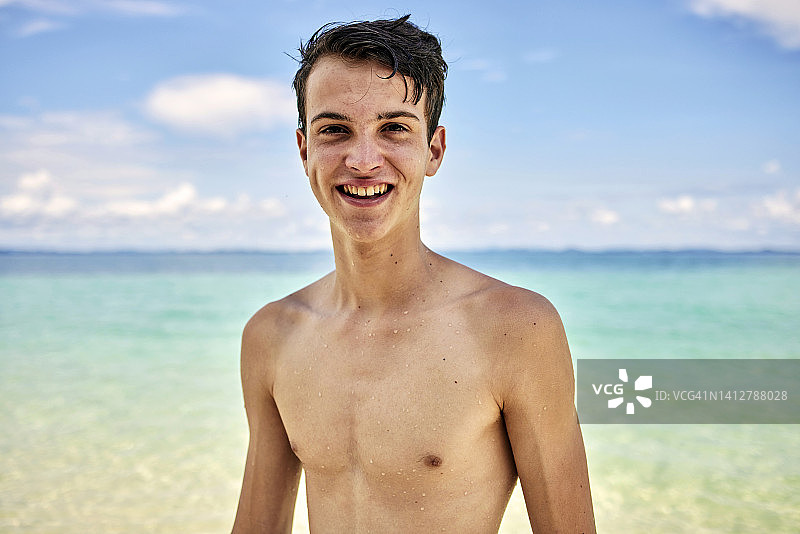 热带海滩上微笑的青少年男性图片素材
