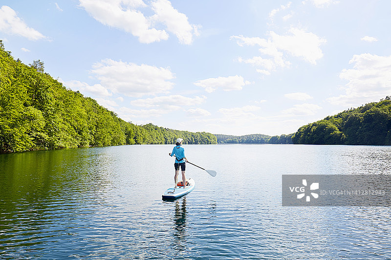 女人在田园诗般的湖面上划桨图片素材