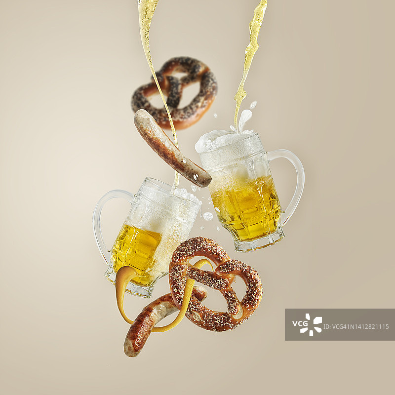 啤酒节概念，玻璃杯中啤酒飞溅，配椒盐脆饼和香肠图片素材
