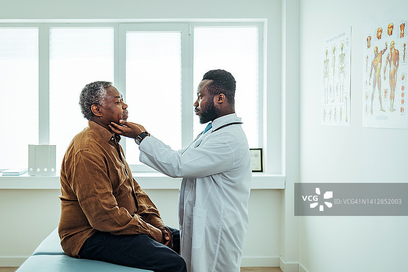 男医生在咨询期间检查老年男人的喉咙图片素材