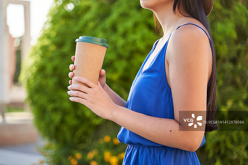 年轻女子手持可重复使用咖啡杯的侧面特写图片素材