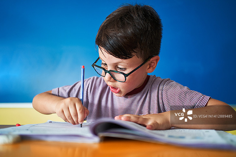 惊讶的男学生在书上写字图片素材