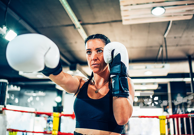 戴拳击手套的运动女人在拳击台上特写图片素材