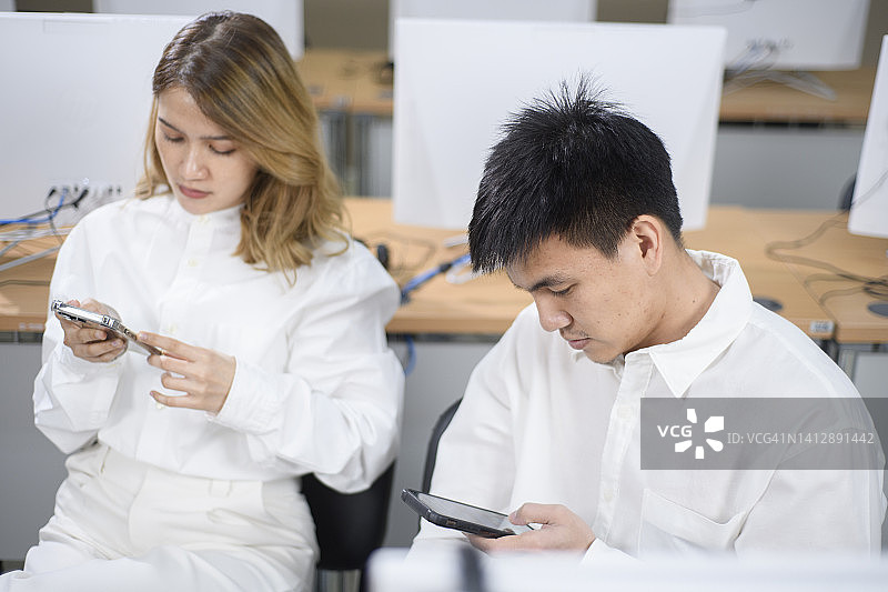 在办公桌前使用智能手机的严肃男女商人图片素材