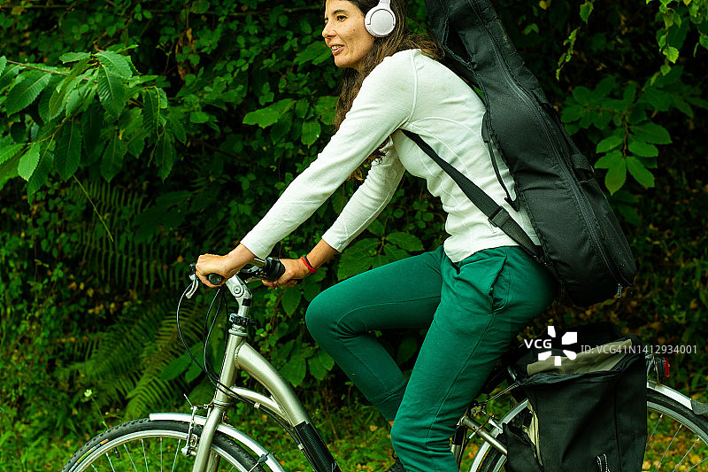 骑自行车背着吉他的年轻女人图片素材