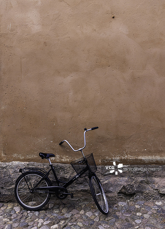 黑色自行车靠在橙色外墙的鹅卵石建筑旁图片素材