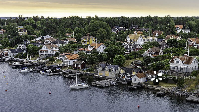 斯德哥尔摩附近美丽群岛的沿海村庄俯视图，日出光辉下的船只和房屋图片素材