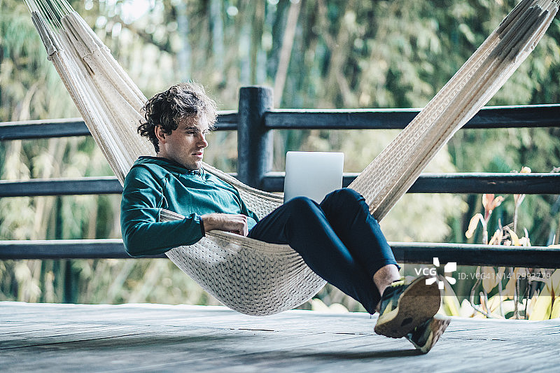 年轻有创意的商务男士在户外吊床上工作图片素材