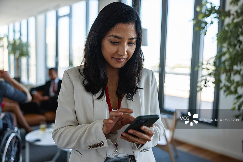 一位亚洲女商人在办公室大厅使用智能手机的画像图片素材