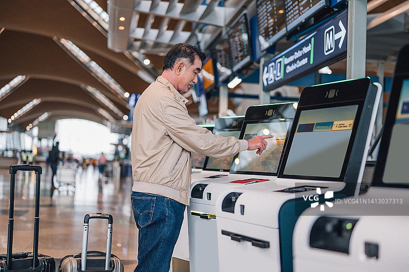 在机场使用自助值机机器的亚洲老年男人图片素材