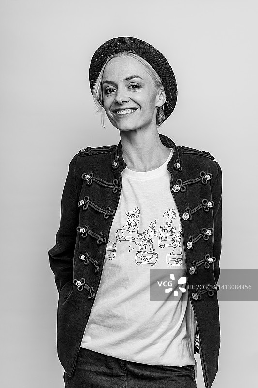 戴着猪肉馅饼帽在灰色背景工作室摆姿势的微笑女人图片素材