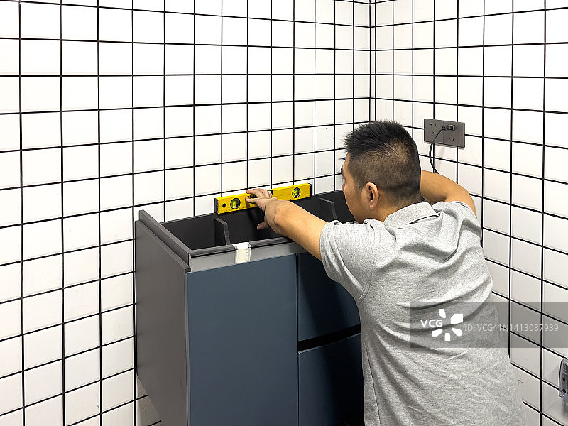中年亚洲男人安装浴室柜图片素材