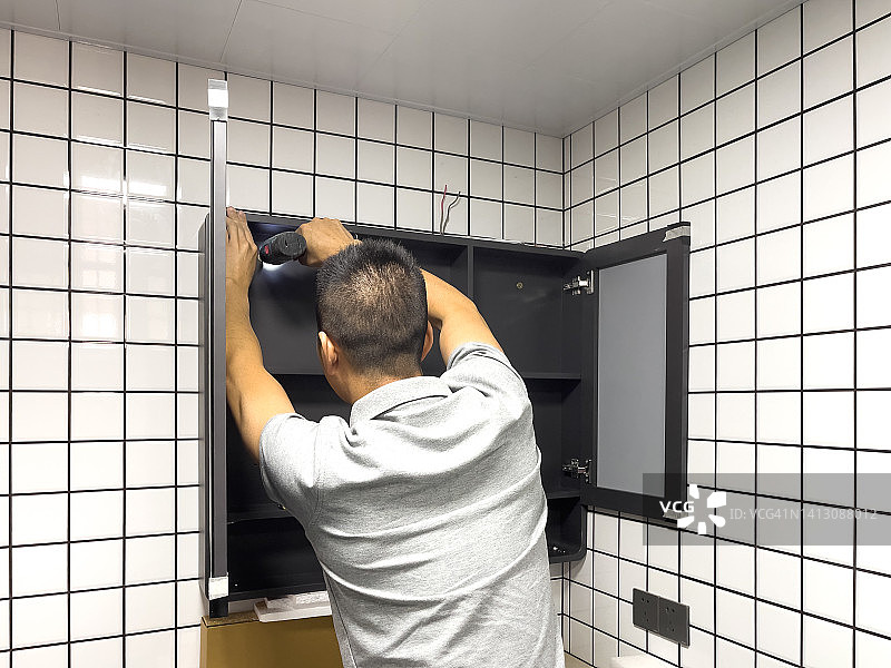 中年亚洲男人安装浴室柜图片素材