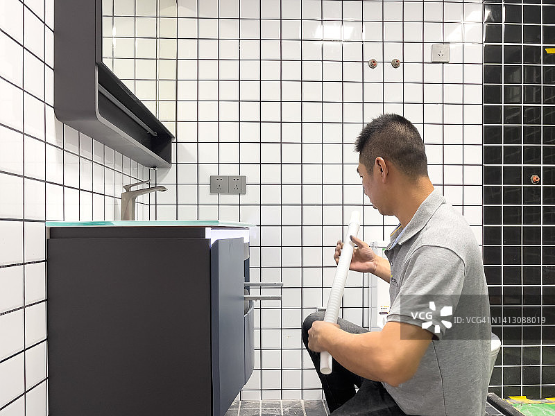 中年亚洲男人安装浴室柜图片素材