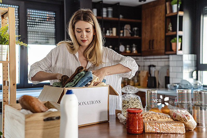 年轻女人打包食物和衣物进行捐赠图片素材