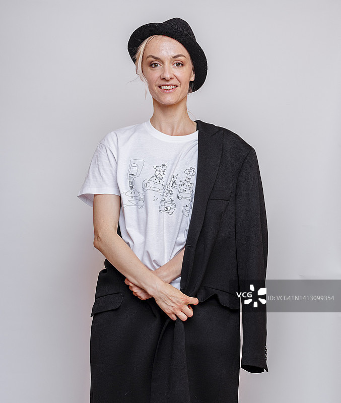 戴着帽子在灰色背景前微笑的女人图片素材