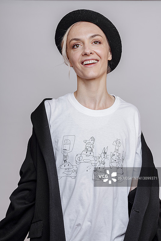 戴着帽子在灰色背景前微笑的女人图片素材