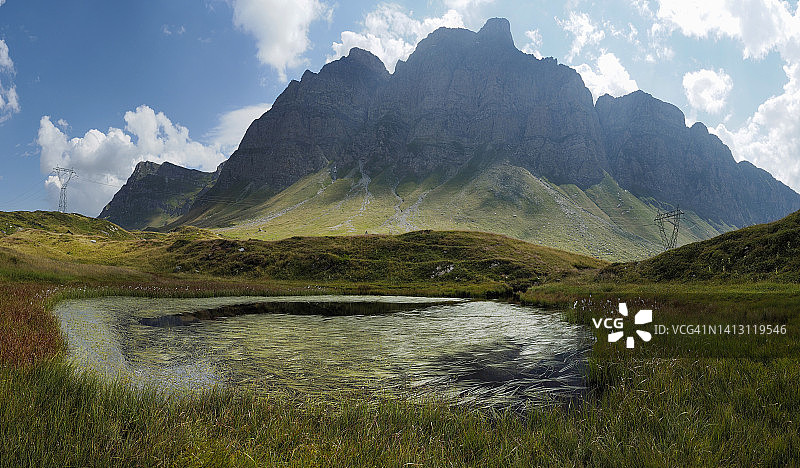 瑞士圣贝纳迪诺山口的卡夫里奥拉山和乌切洛山与小池塘图片素材