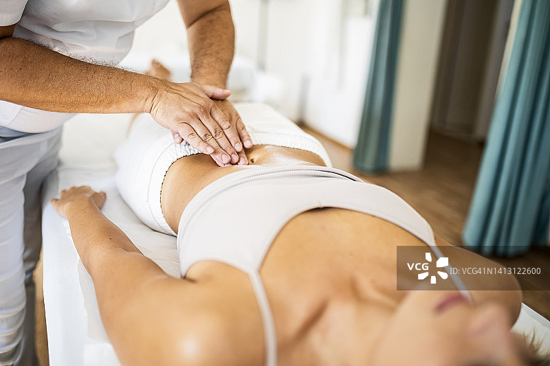 专业按摩师进行腹部穴位治疗按摩图片素材