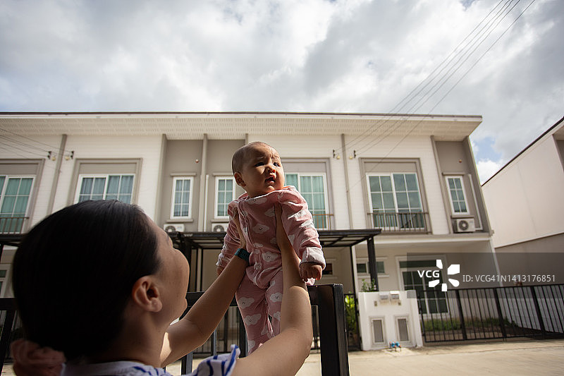 快乐的母亲和女儿在房子前玩耍图片素材