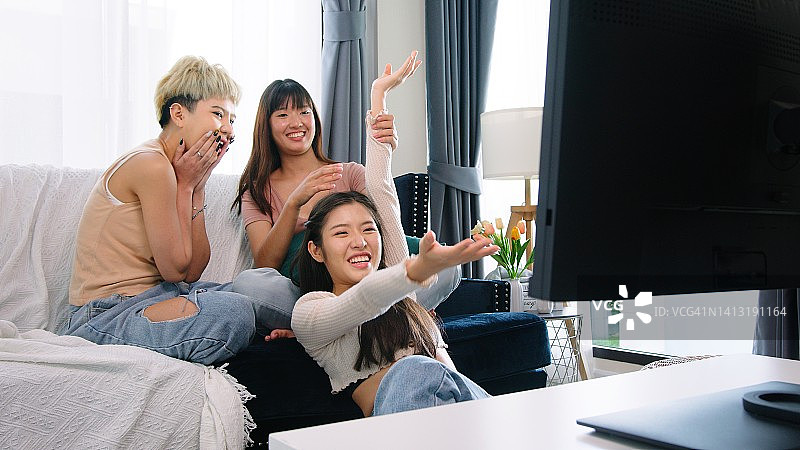 三个女人在客厅里看电影的快乐时光：大学同学友谊聚会图片素材
