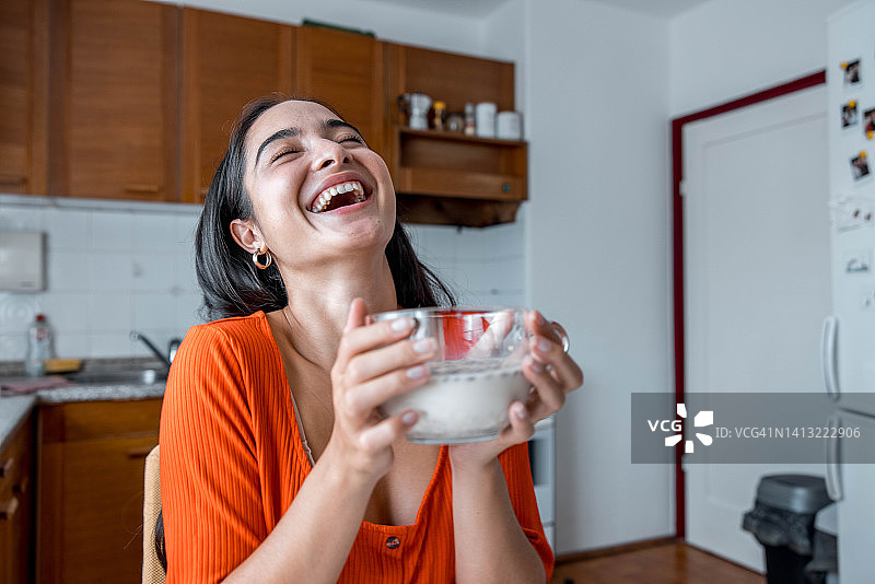 在厨房里拿着麦片碗玩耍的女人图片素材