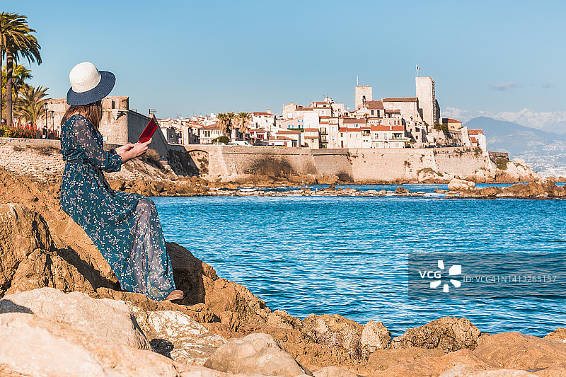 游客在法国蓝色海岸昂蒂布的背景下阅读图片素材