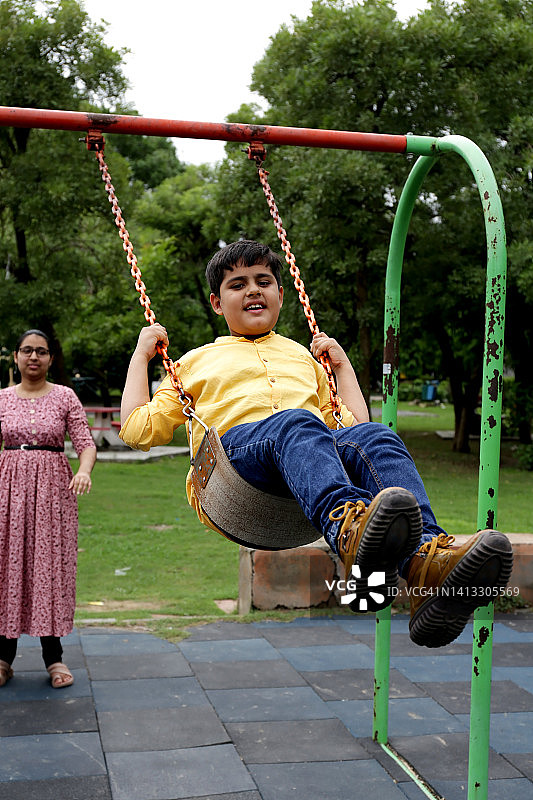 姐姐在公园推弟弟荡秋千图片素材