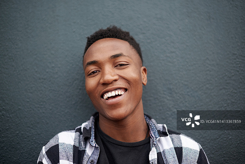 近距离拍摄的休闲、快乐、放松的黑人男学生，靠墙站立，享受空闲时光图片素材