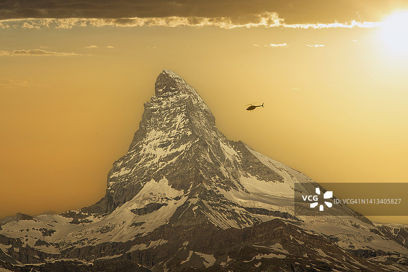 直升机飞越日落时分的马特洪峰图片素材