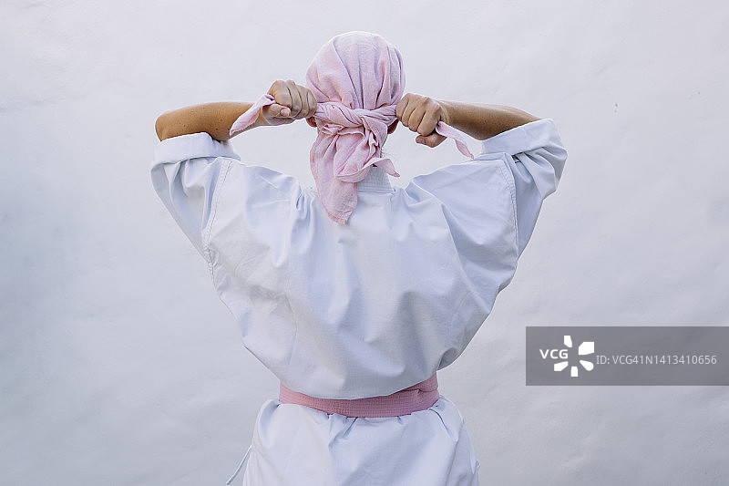 戴着粉色头套、穿着粉色腰带空手道服的女子背影：对抗癌症概念图片素材
