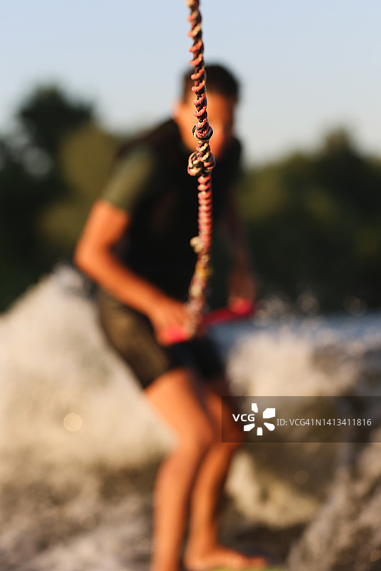 年轻女子在船后进行尾浪冲浪训练的剪影图片素材