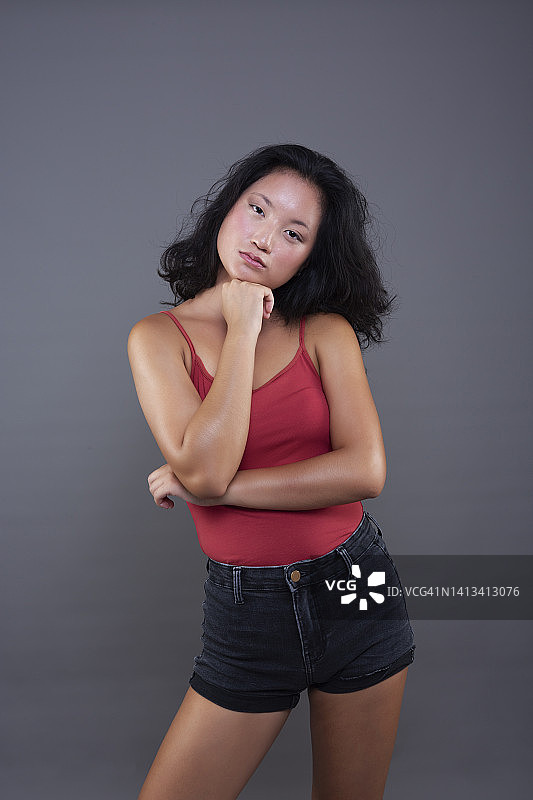 手托下巴，表情严肃的年轻中国女人图片素材