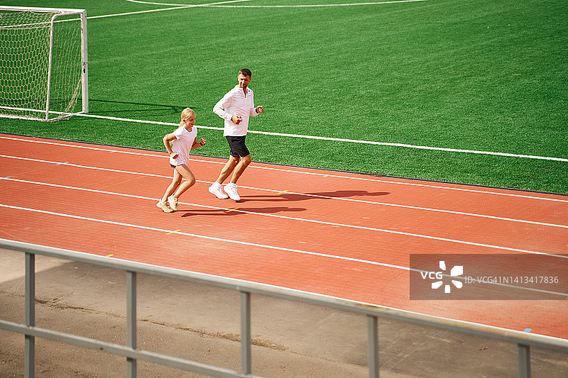 父亲在田径体育场训练女儿图片素材
