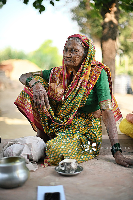 坐在房屋前院的印度农村老妇人肖像图片素材