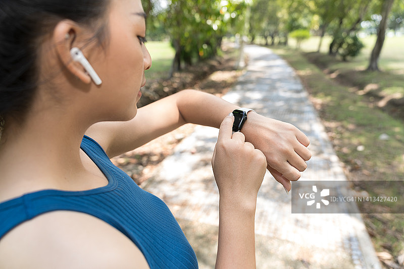 在公园锻炼、看智能手表、准备慢跑的亚洲女性图片素材