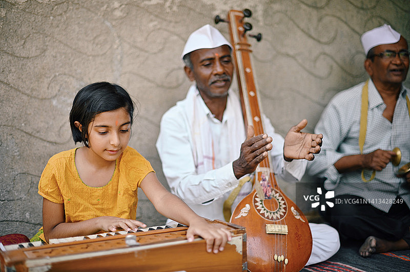 女孩演奏风琴，其他长者演奏西塔琴和钹图片素材