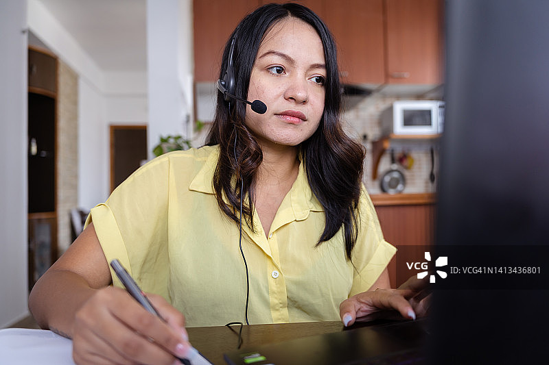 在办公桌前使用耳机的印度女商人图片素材