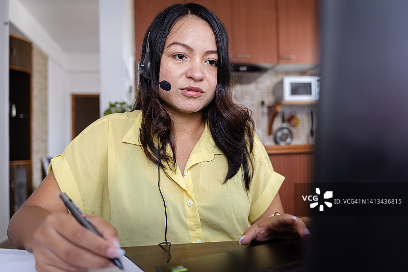 在办公桌前使用耳机的印度女商人图片素材