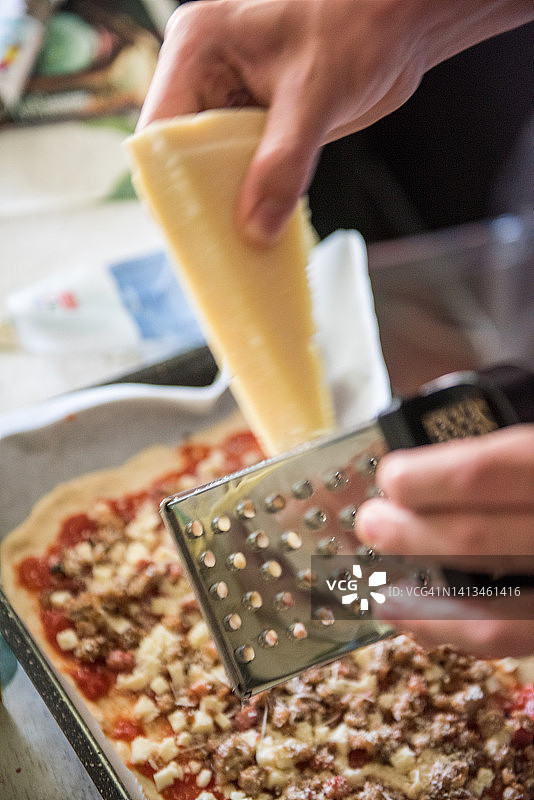 在四种奶酪披萨上磨碎帕尔马干酪，配火腿和香肠图片素材