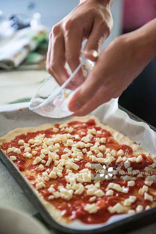 在披萨上添加马苏里拉奶酪图片素材