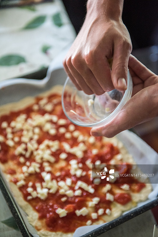 在披萨上添加马苏里拉奶酪图片素材