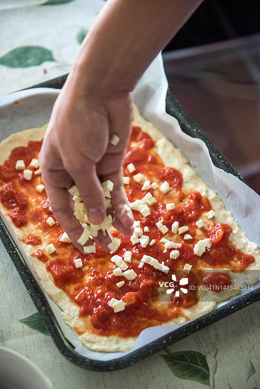 在披萨上添加马苏里拉奶酪图片素材