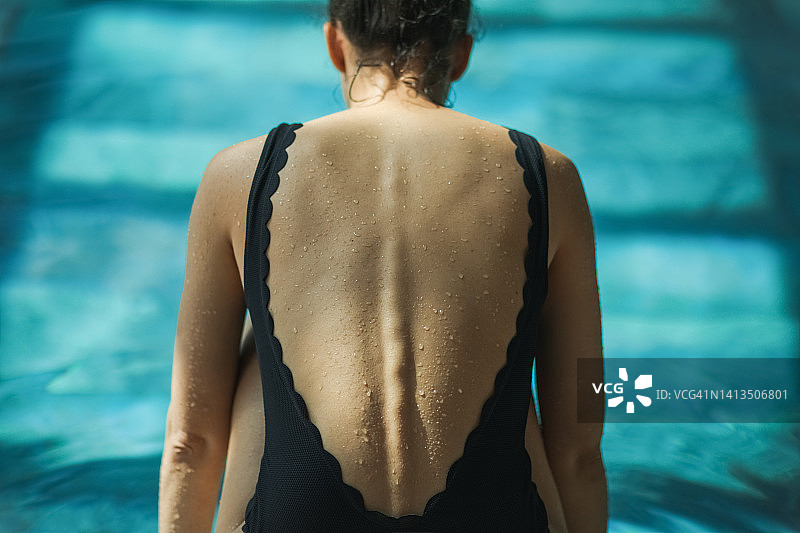 游泳池背景下的女性背部水滴特写：水中性感身姿图片素材