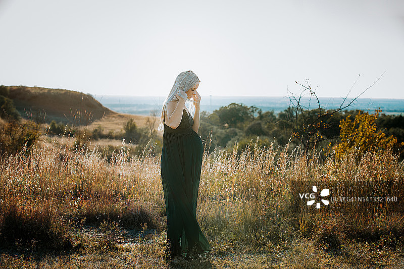 站在田野里的美丽金发孕妇的孕期照片拍摄图片素材