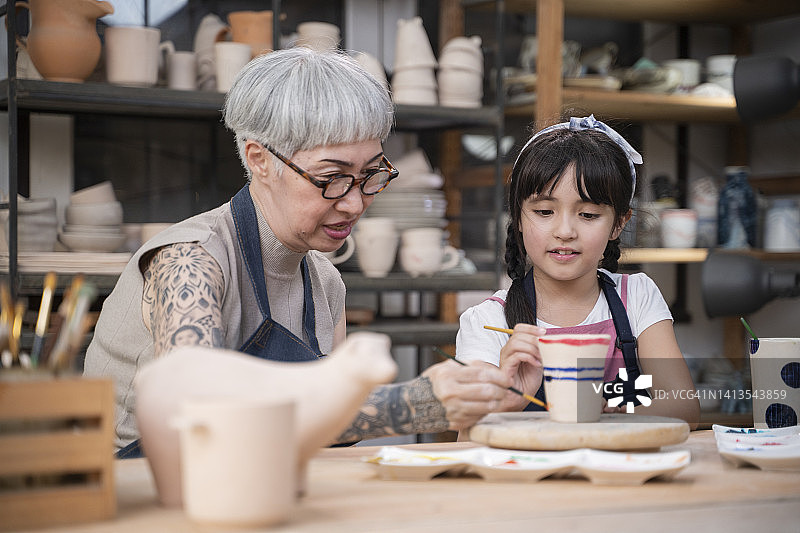 老妇人教年轻女孩画陶器图片素材